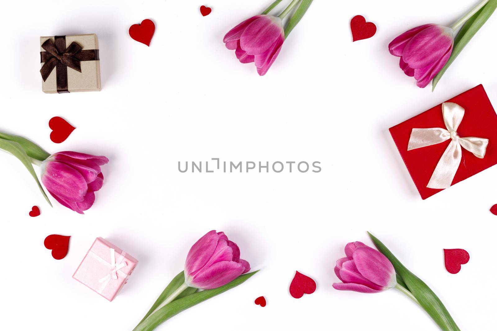 Flat lay valentines day frame with pink tulips hearts and gift boxes on a white background