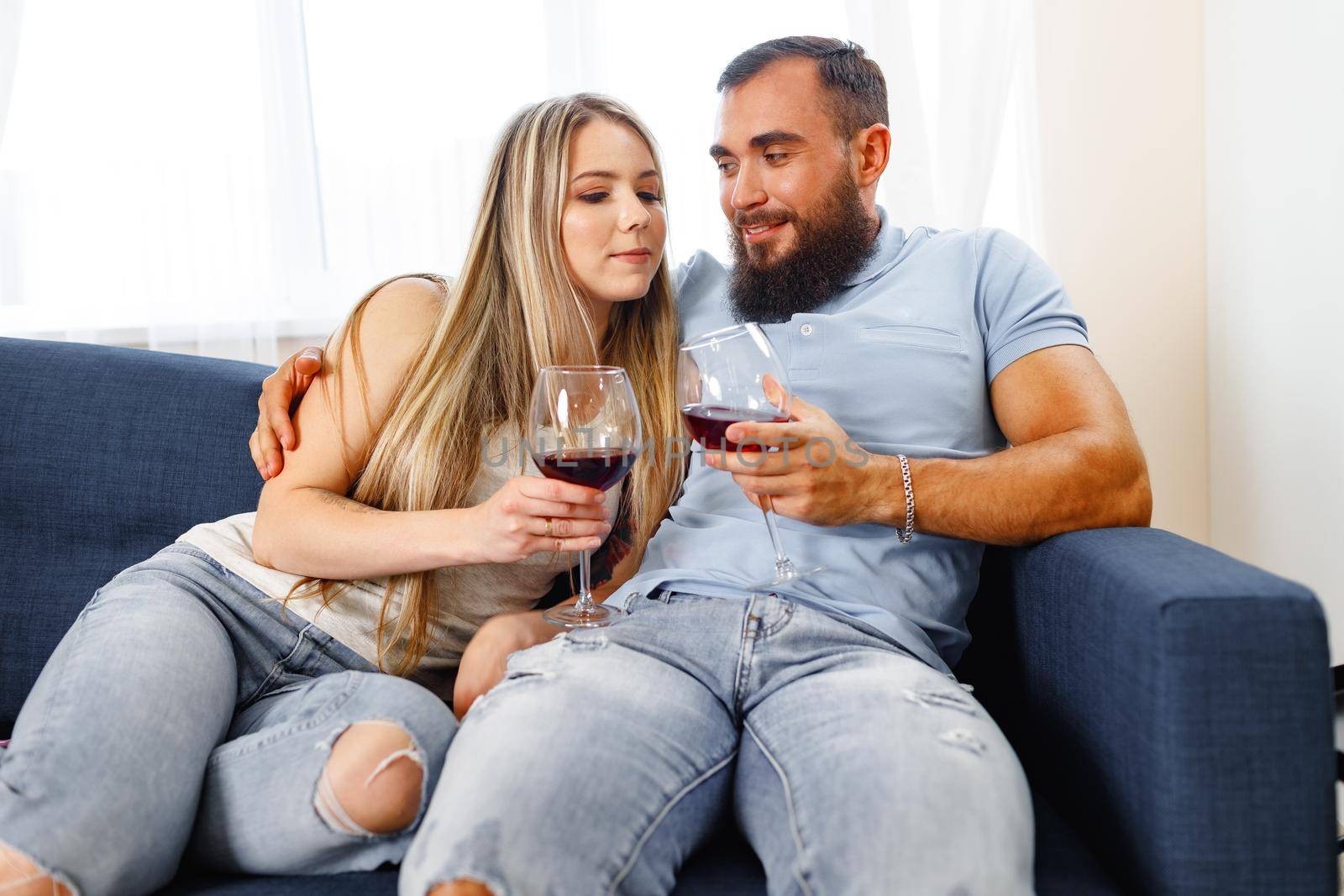 Couple sitting on sofa at home and drinking wine, close up