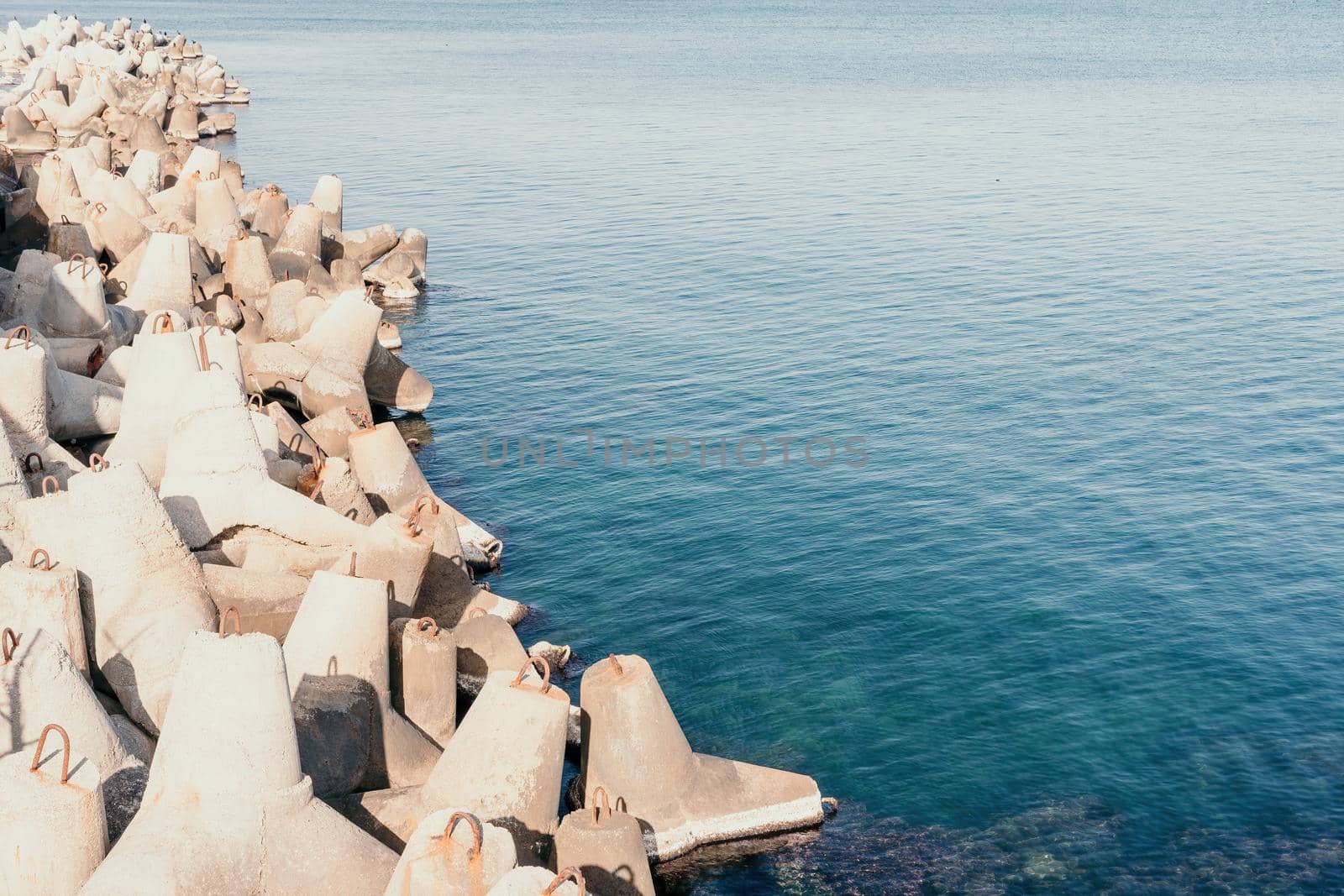 The seashore is reinforced with concrete tetrapods. Protection of the shore from blurring. Sea waves. Concrete tetrapod breakwaters lie all along the coast.
