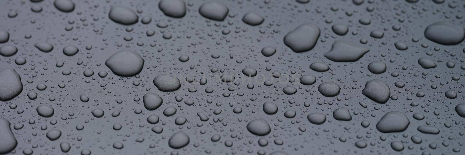 Closeup of raindrops on dark glass background. Oleophobic surface concept