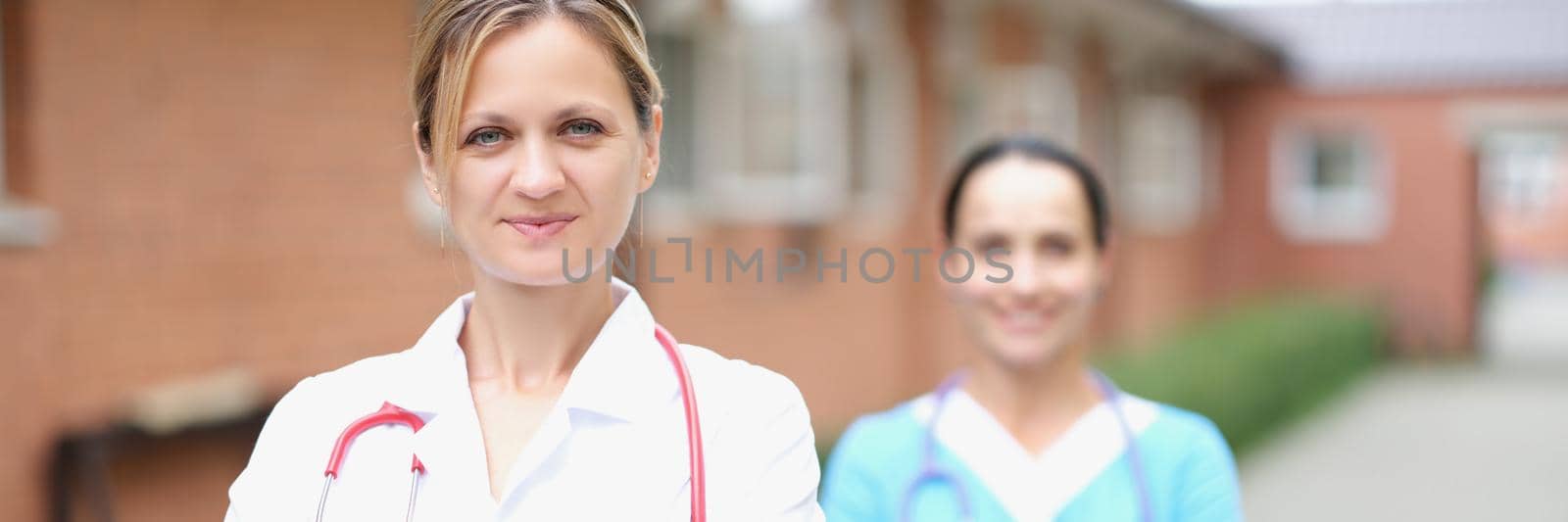 Female doctor with stethoscope standing near medical clinic. Professional medical assistance concept
