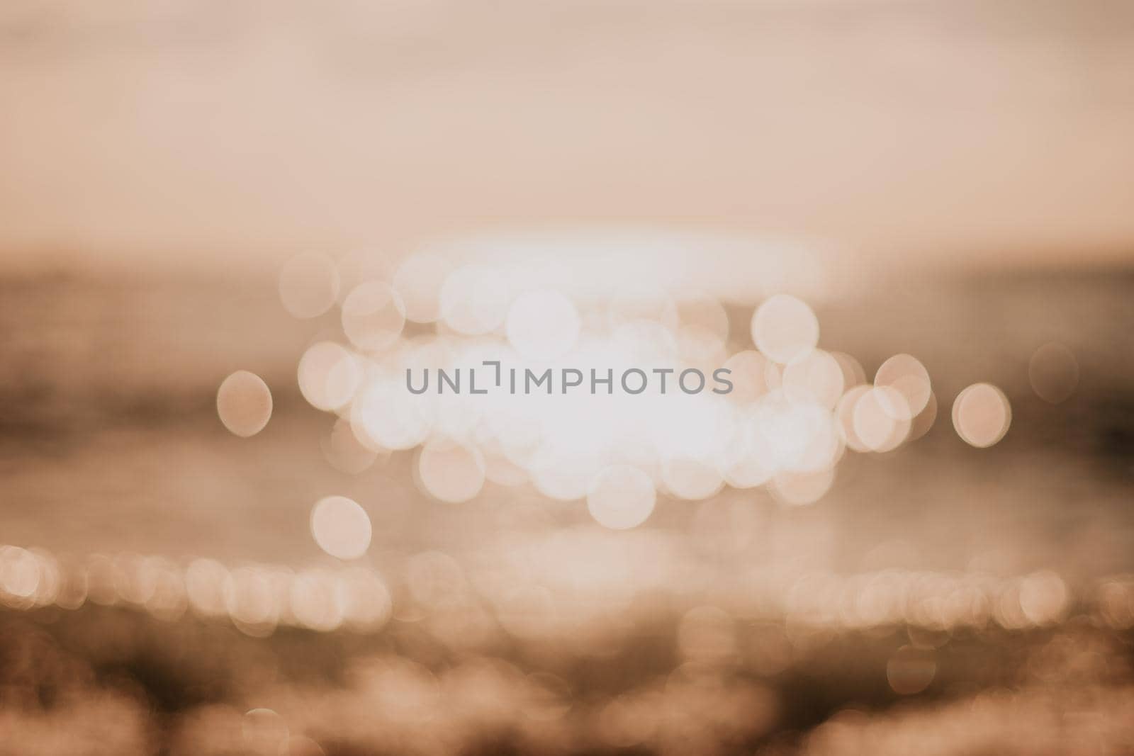 Abstract nature summer or spring ocean sea background. Small waves on water surface in motion blur with bokeh lights from sunrise.