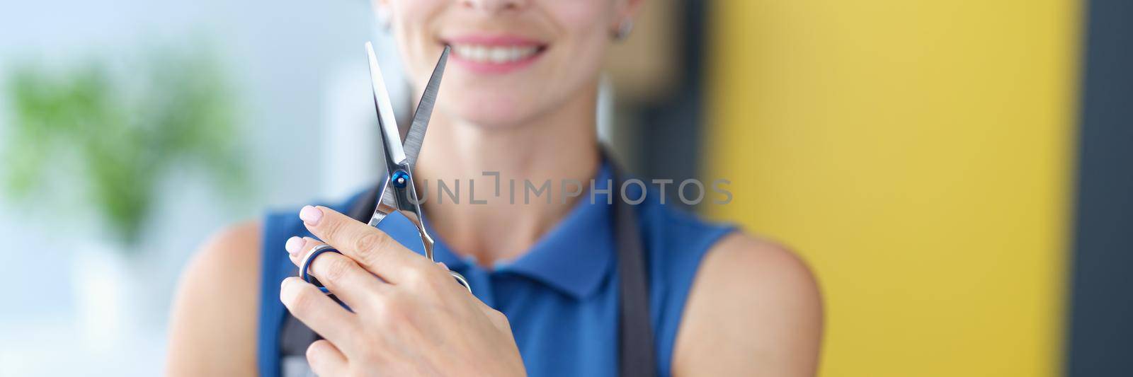 Woman hairdresser in glasses holding professional metal scissors in hands closeup. Training in hairdressing master classes concept