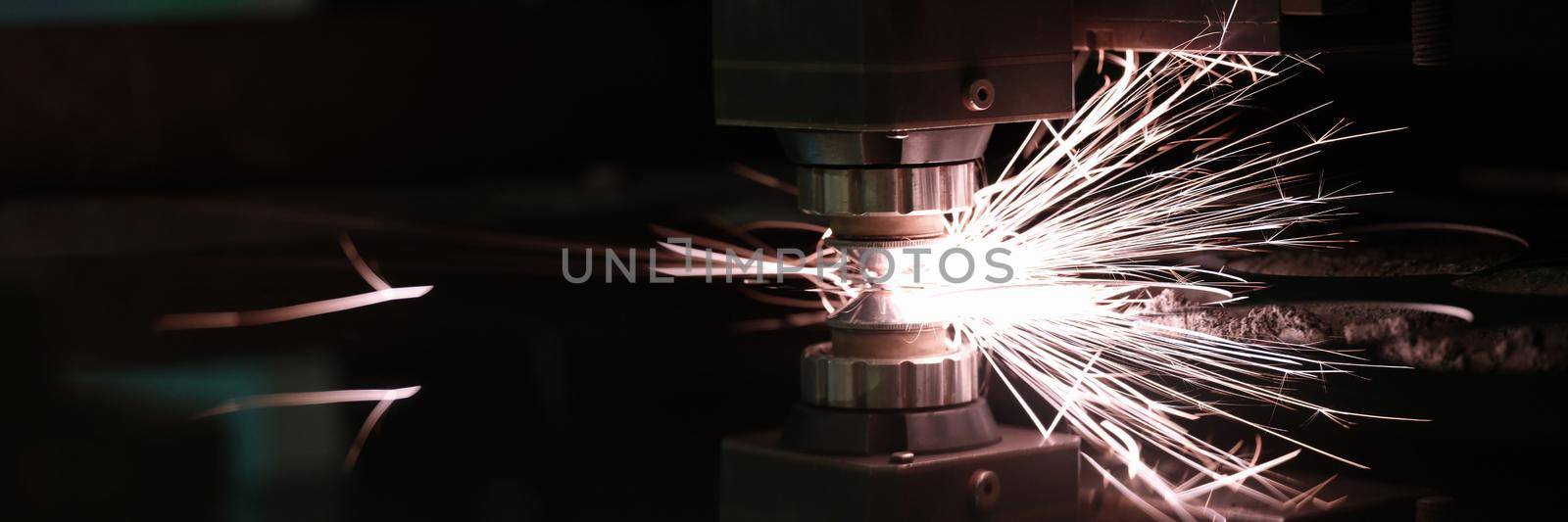 Laser machine cutting steel sheet with bright sparks closeup by kuprevich