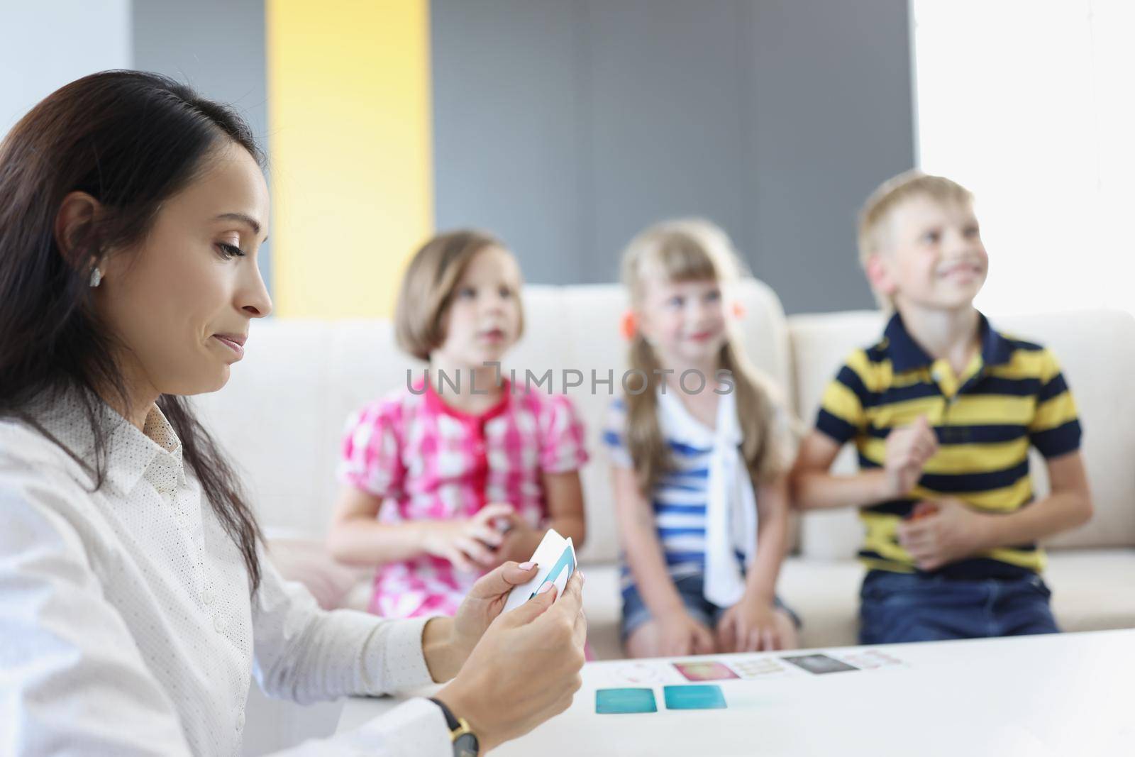 Portrait of group of kids spend time in kindergarten with female teacher. Mother entertain children with games on holiday. Childhood, fun, family concept