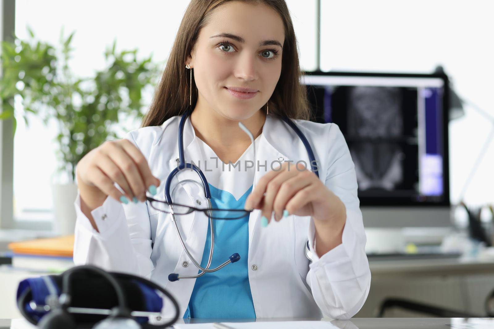 Young woman doctor sit in office at work in hospital by kuprevich