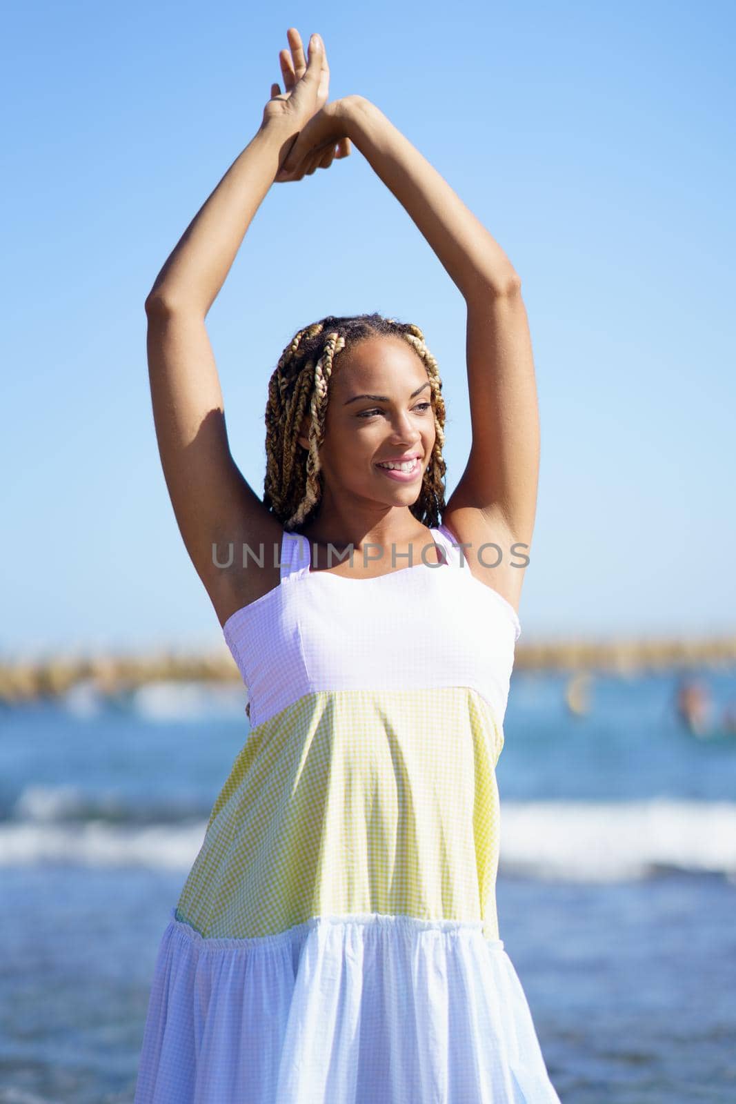 Black girl walking along the shore of the beach wearing a beautiful long dress. by javiindy