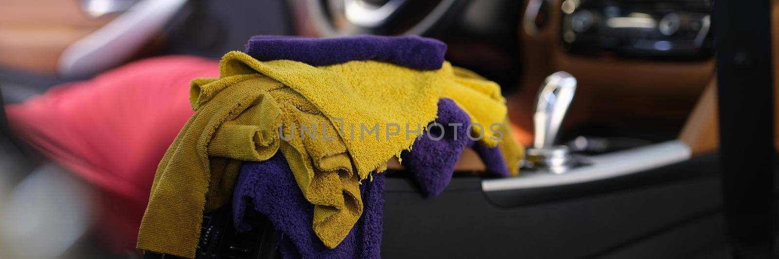 Multicolored microfiber rags lying in car interior closeup. Car cleaning service concept