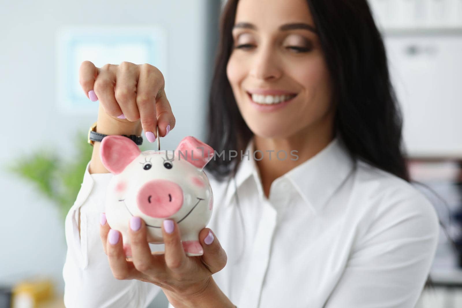 Portrait of happy woman putting coins in piggybank container and smiling. Save money, collect cash, take care of tomorrow. Saving up, investment, concept