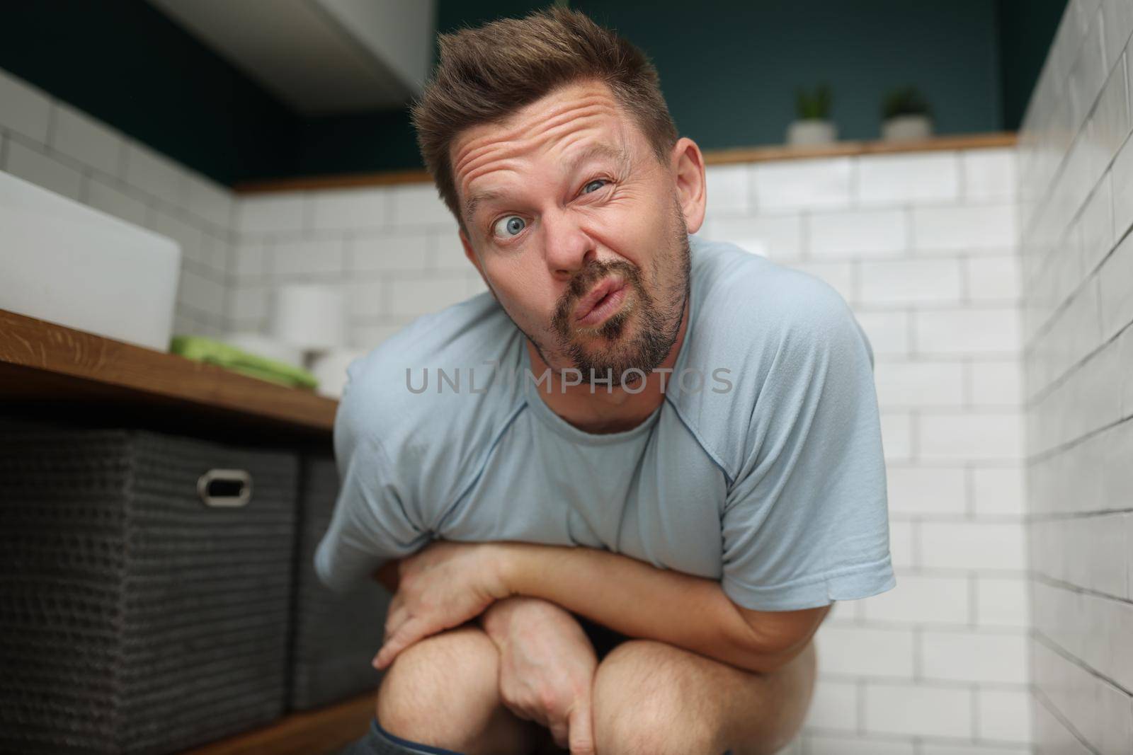 Man with funny facial expression on toilet seat, fulfill natural need by kuprevich