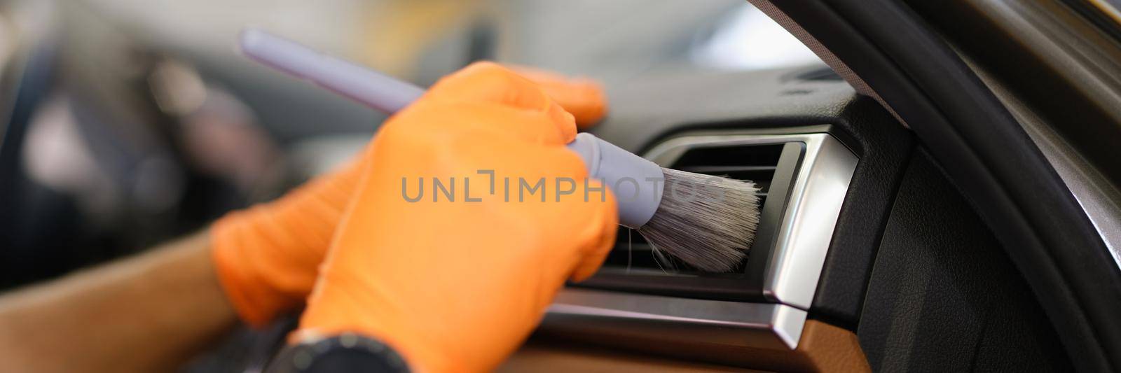 Master mechanic in rubber gloves wiping air conditioner of car with brush closeup. Car cleaning service concept
