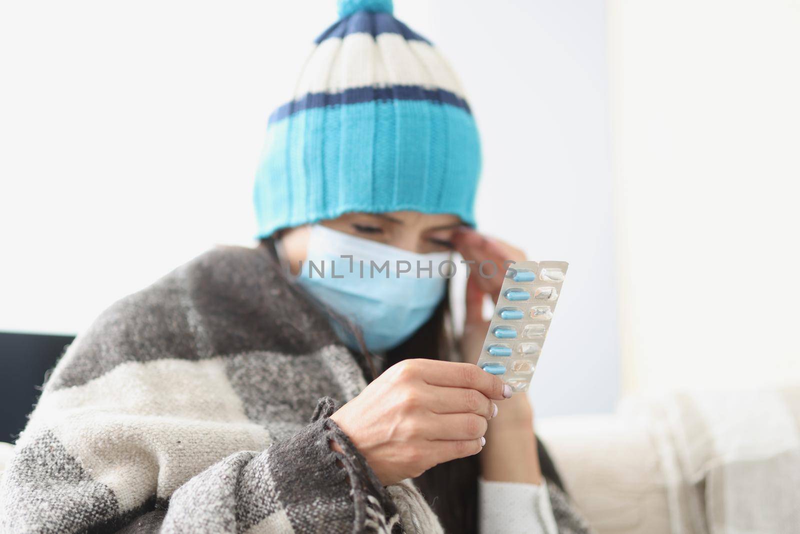 Portrait of woman hold blister with tablets in hand, feeling unwell, bad headache. Female on quarantine at home, self isolation. Health, sickness concept