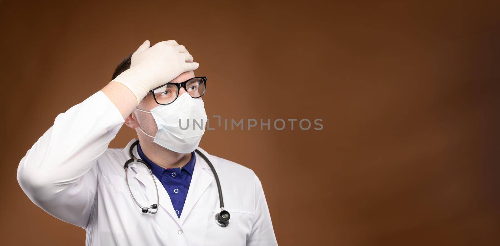 panoramic Young caucasian doctor in a medical uniform makes a facepalm gesture. Medical errors and stupidity.