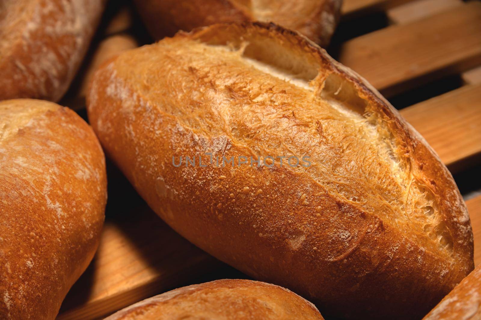 Appetizing fresh hot artisan bread. Close-up of a loaf of delicious bread on a wooden pallet.