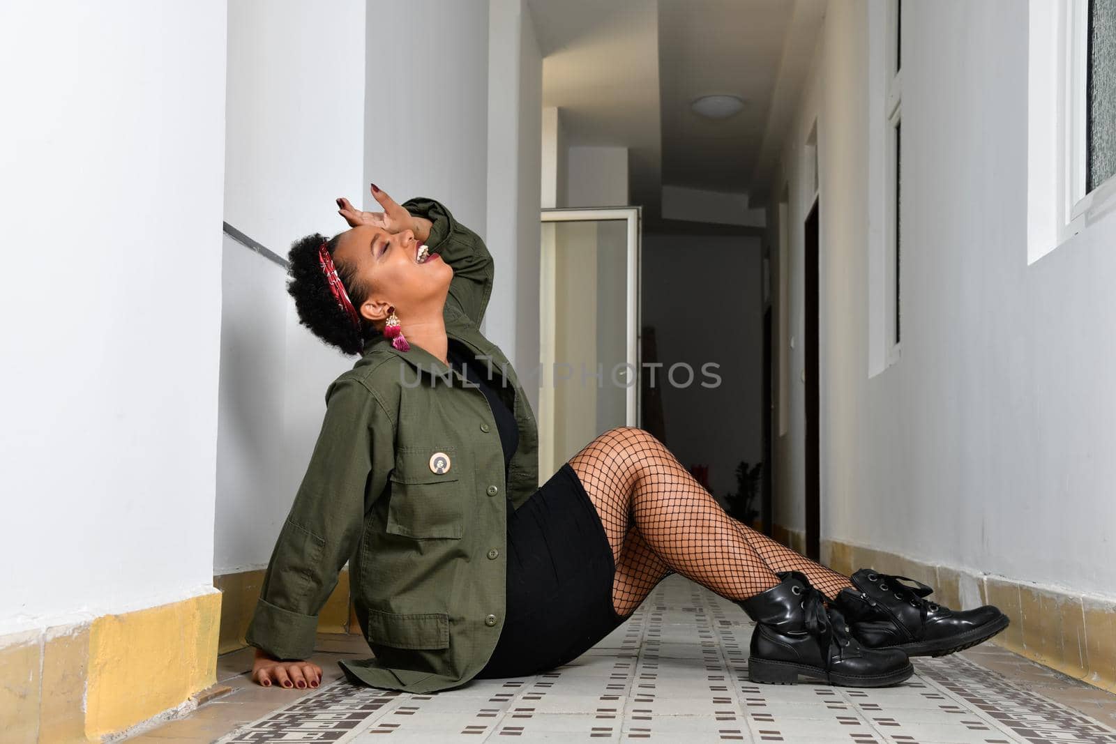 A pretty young African American confident woman in the stairwell of an old apartment building.