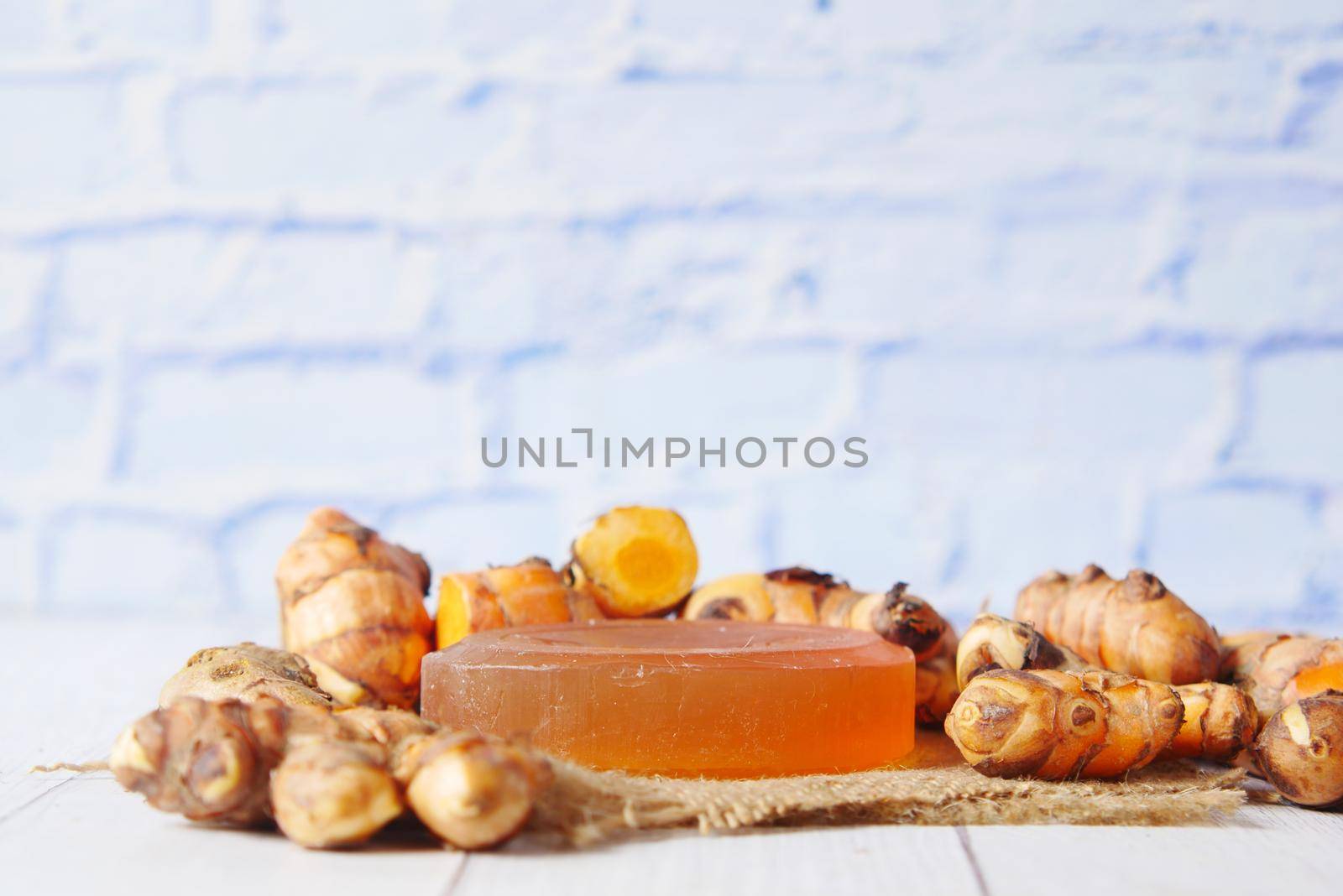 turmeric root and herbal soap on table ,
