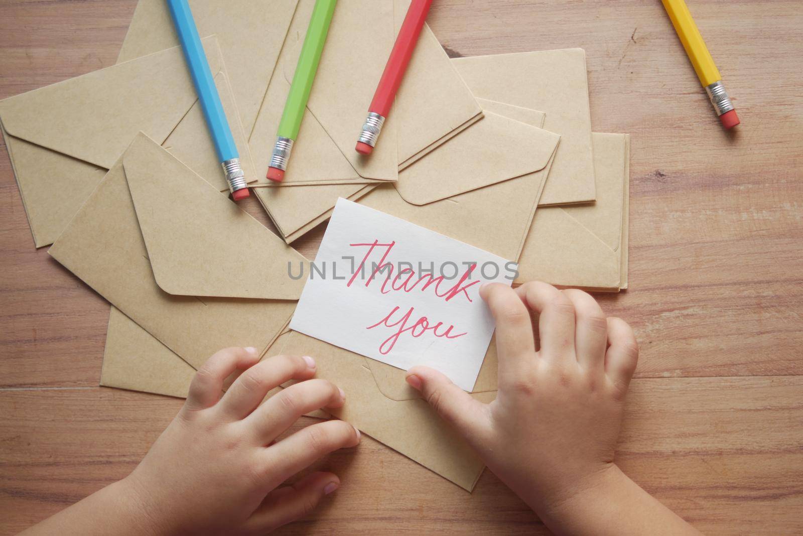 child hand holding thank you letter on table ,