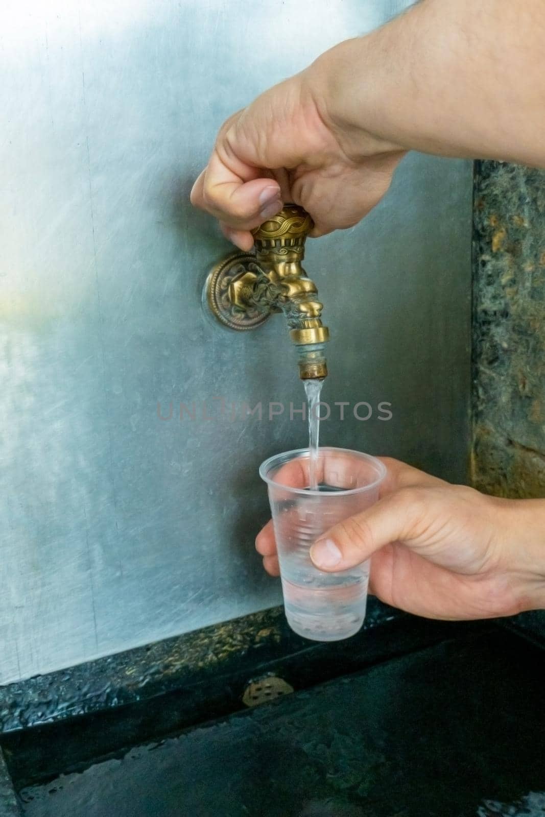 Pouring mineral thermal water into the disposable cup at the pump-room, close-up. narzan spring in Kislovodsk, Russia. High quality photo