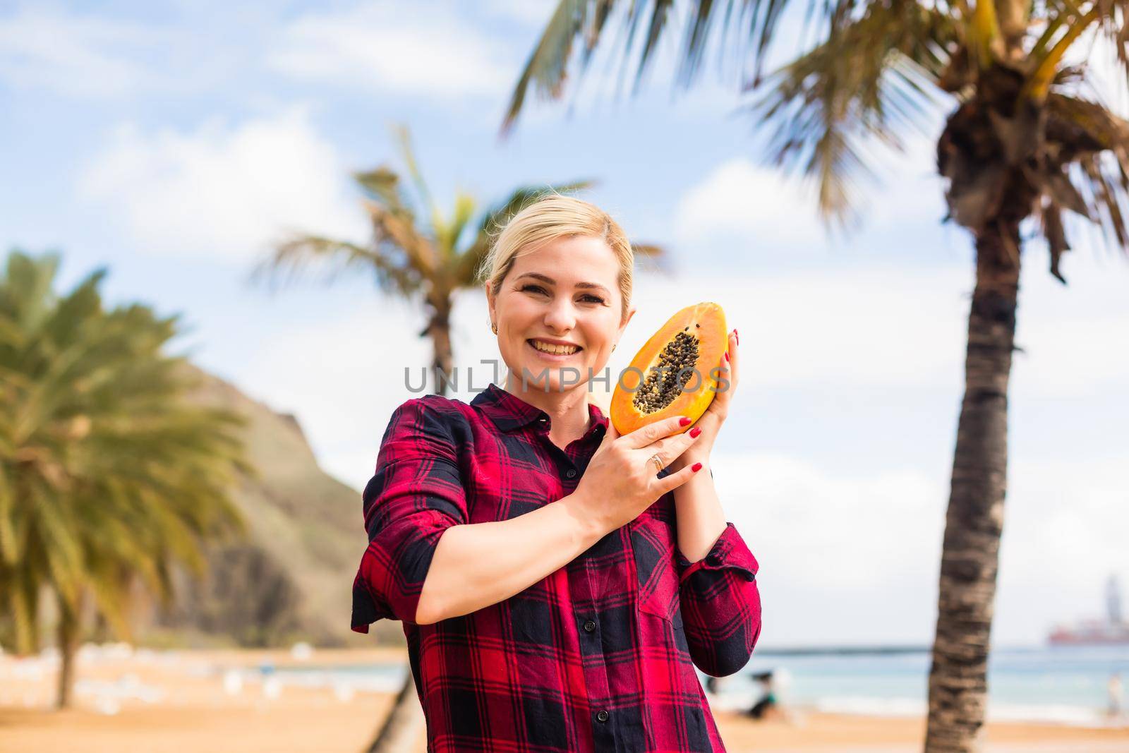 woman holds papaya on the beach