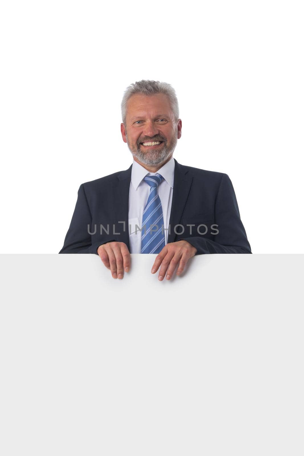 A smiling mature businessman holding a white panel and gesturing isolated on white background