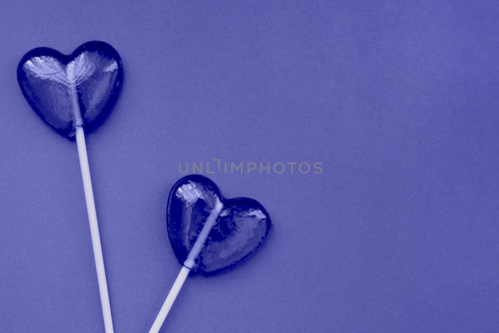 Purple lollipops in the form of hearts on a purple background. The concept of Valentine's Day. Demonstrating the colors of 2022 - Very Peri.