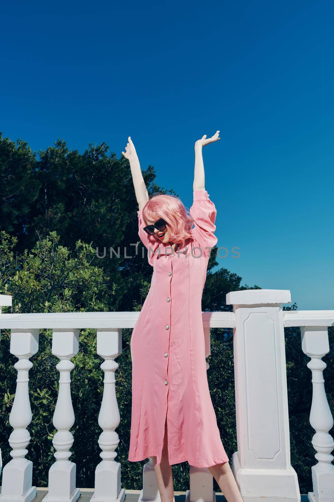 attractive woman pink dress modern style stands near the railing unaltered. High quality photo
