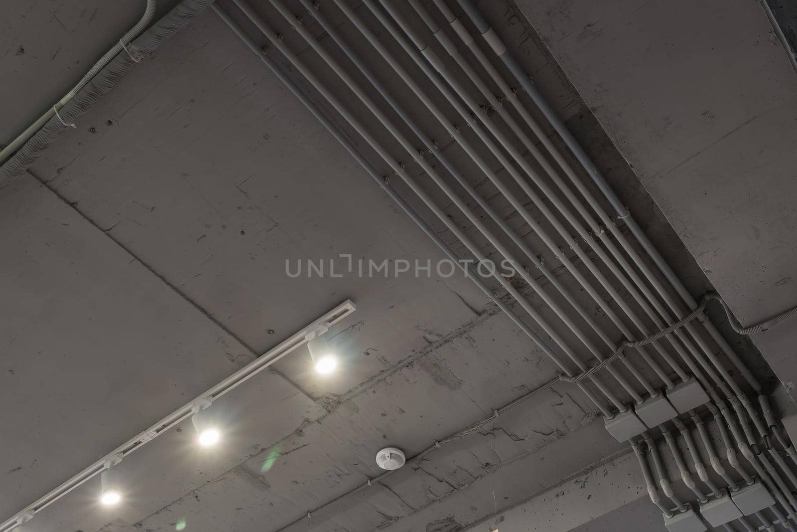 Abstract loft interior of concrete grey ceiling with air ventilation and security camera. Interior architecture and ceiling design of industrial loft building decorated with modern lamps by panophotograph