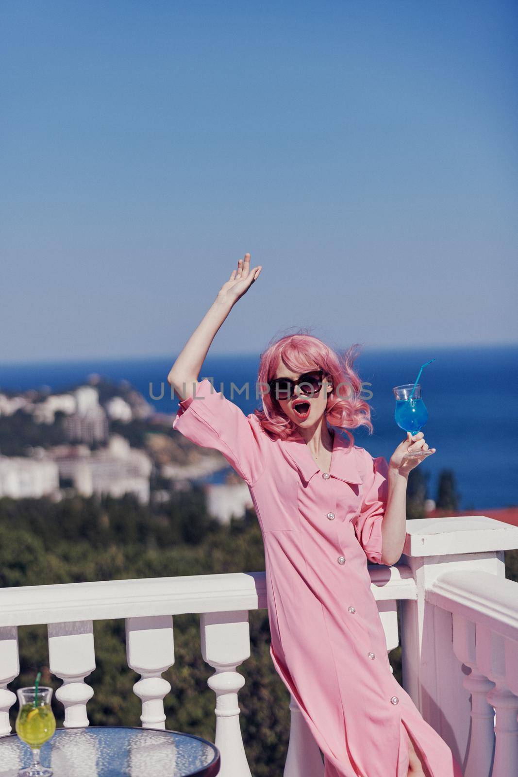 Delighted young girl enjoying a colorful cocktail on the panoramic view hotel terrace Relaxation concept. High quality photo