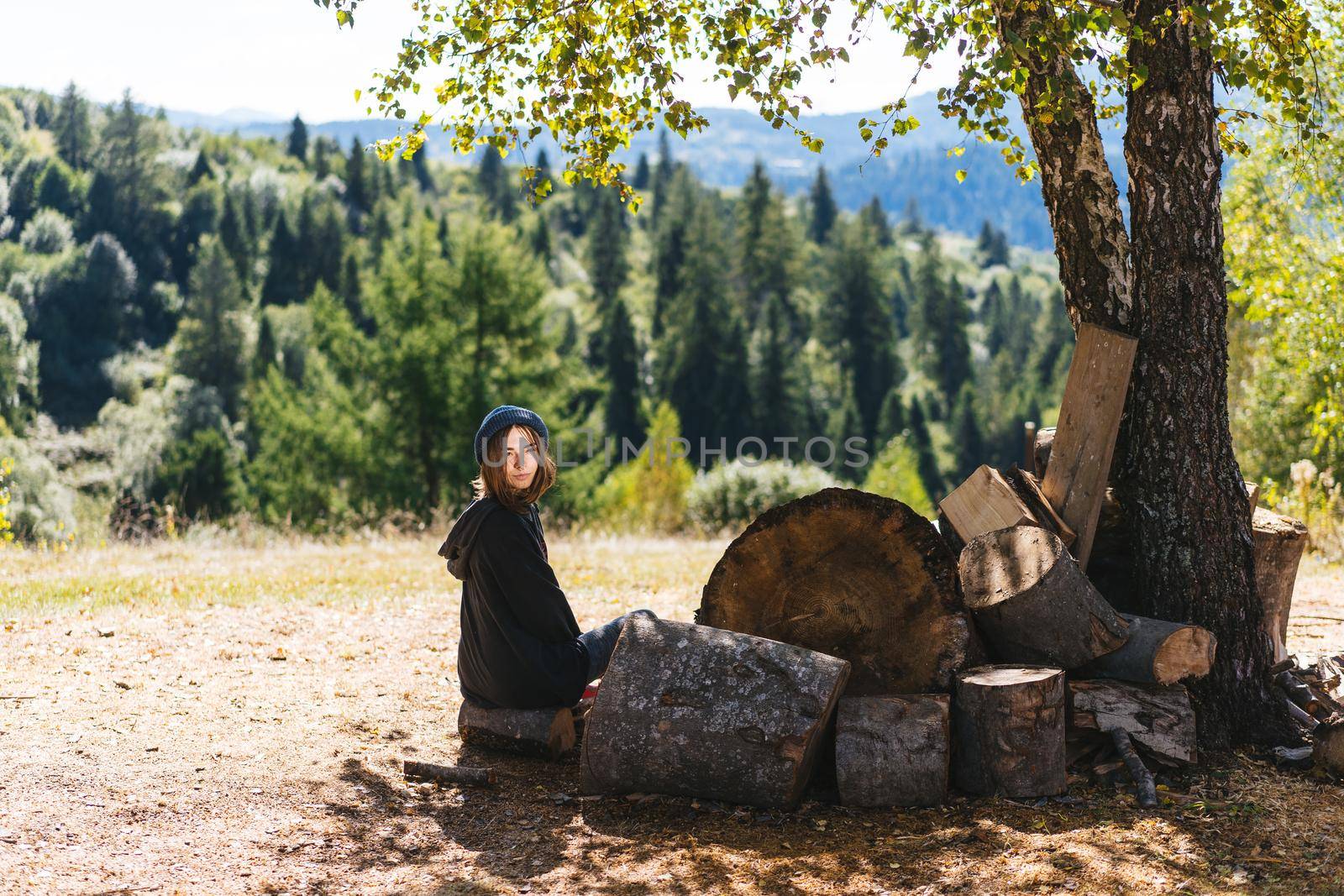 Woman next to logs of cut wood