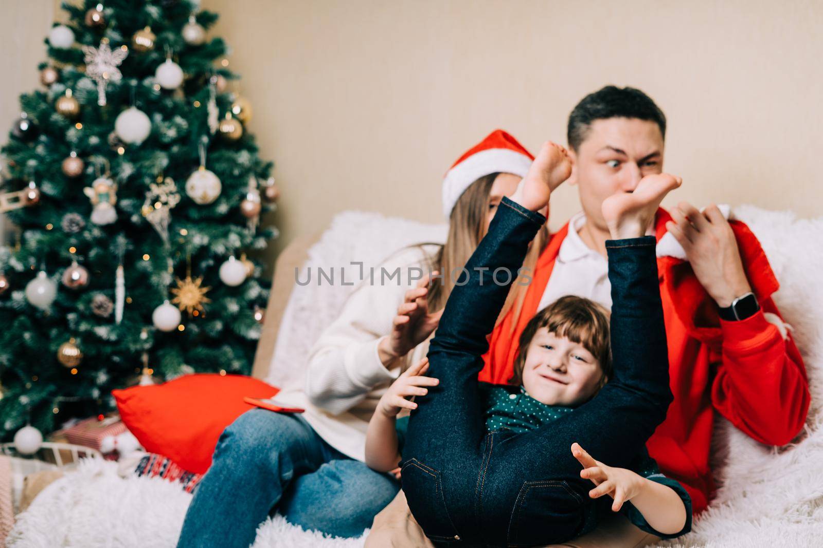 Happy smiling family having fun and fool with kid son. Laughing mother in Santa hat, father, child boy in sweater having fun on Christmas holidays at home. Merry Christmas and happy new year by Ostanina