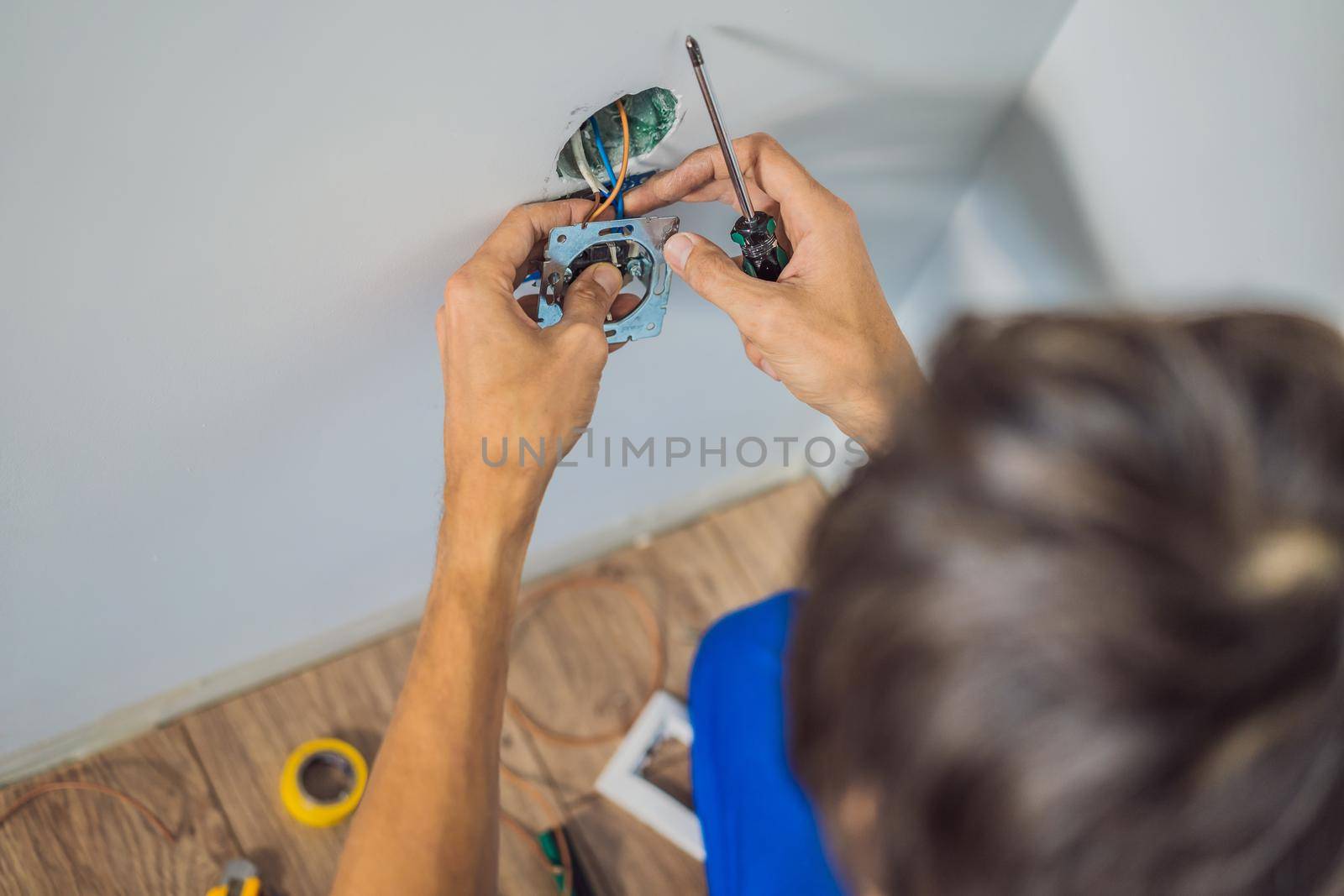 Master electrician installs a socket in the house.