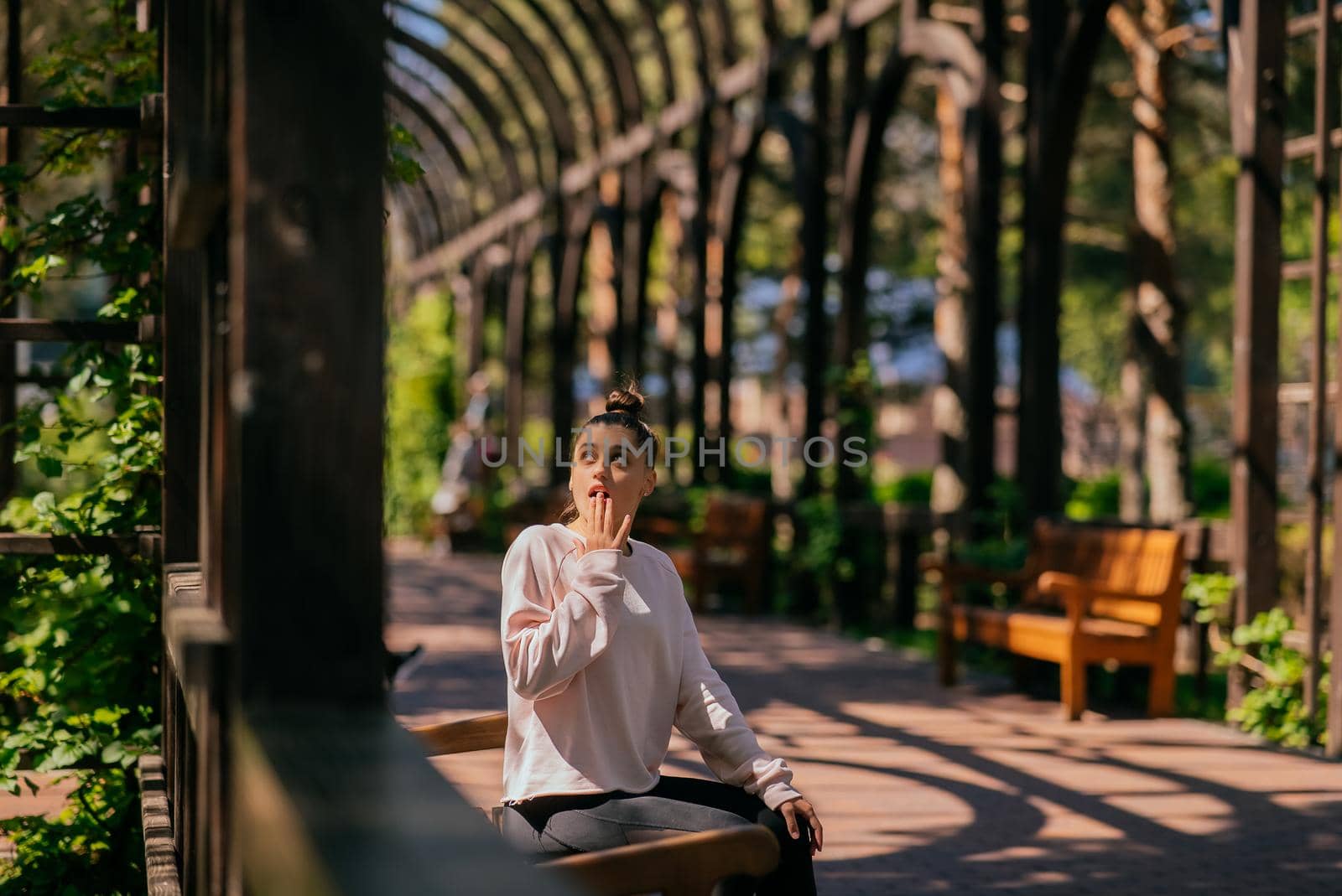 Woman walks along a picturesque alley in summer park.