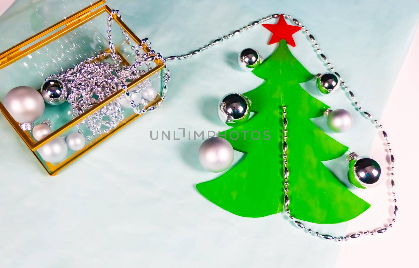 silver ornaments come out of a glass and gold casket and decorate a flat Christmas tree on a black and blue background. minimalistic christmas decoration concept. High quality photo