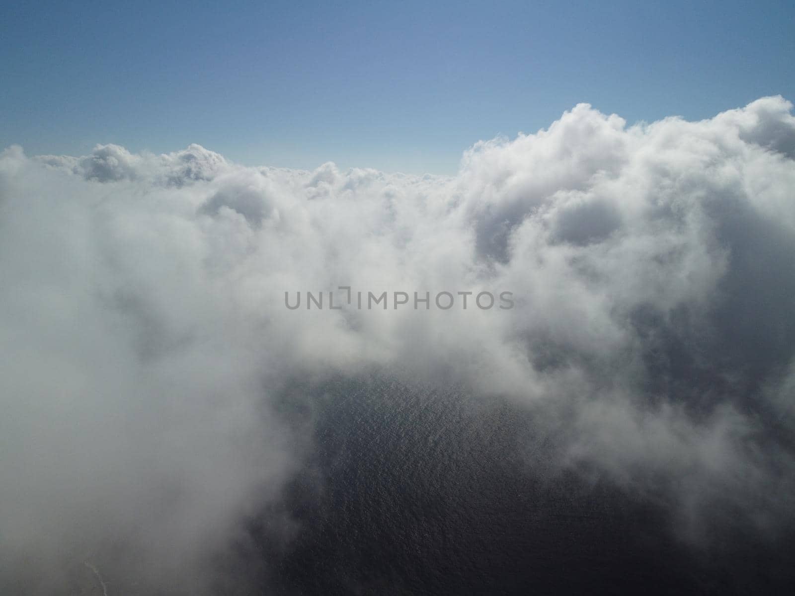 Aerial view. The drone flies over foggy and fluffy clouds. Blue sky sun and sea fog. Abstract aerial nature summer ocean sunset sea and sky background. Vacation, vacation and holiday concept by panophotograph