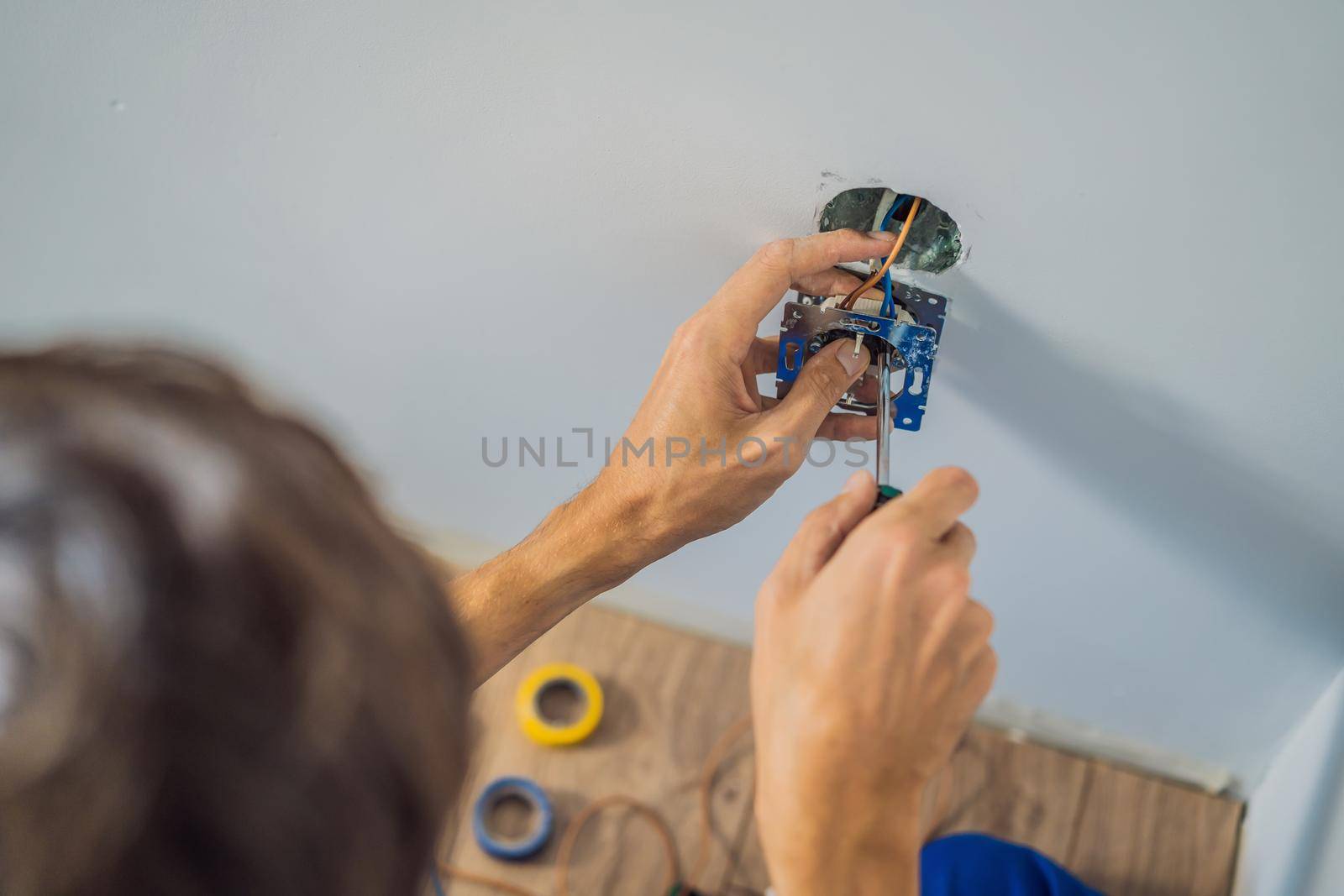 Master electrician installs a socket in the house.