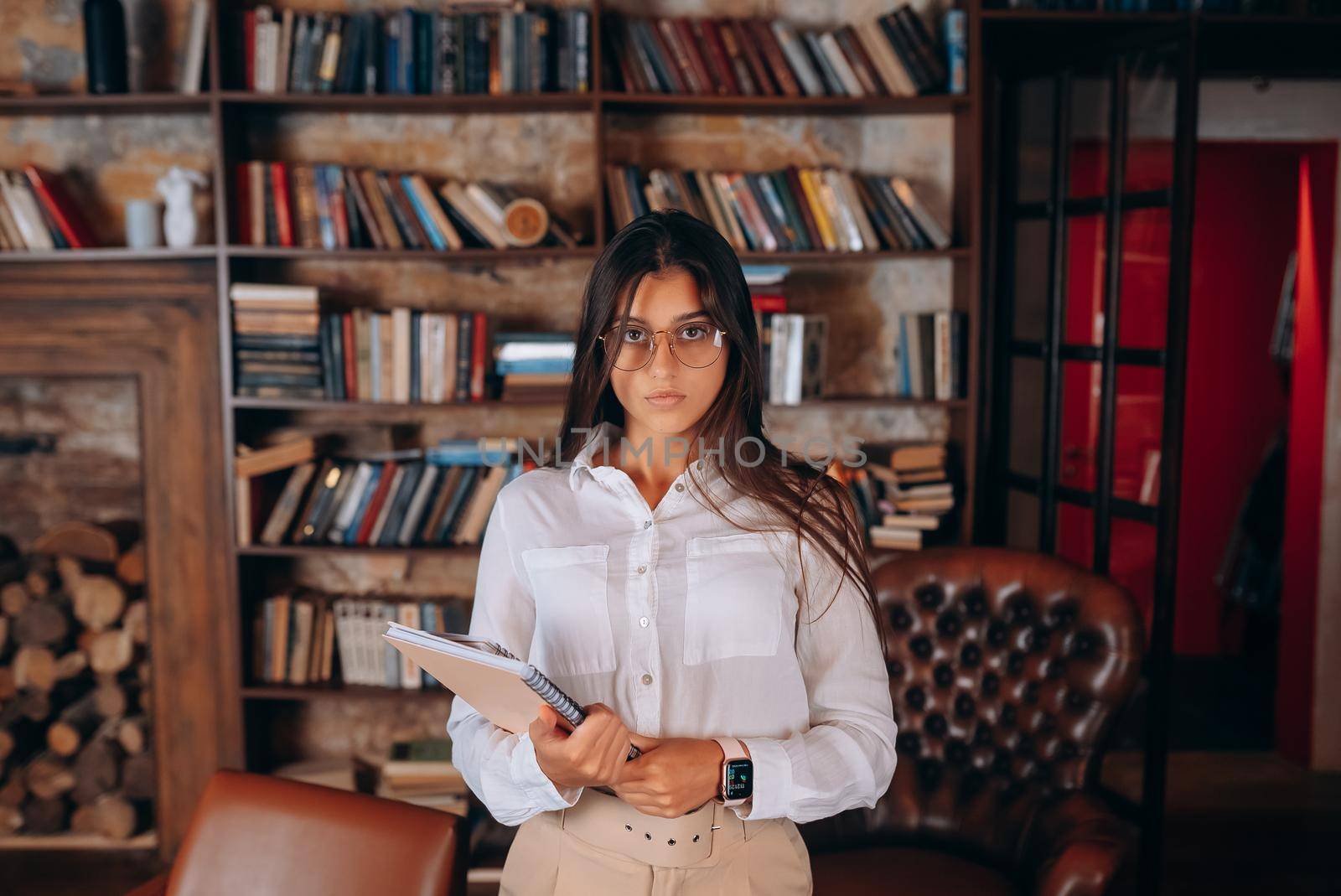 Young woman with documents in hands on the background of a bookshelf by teksomolika