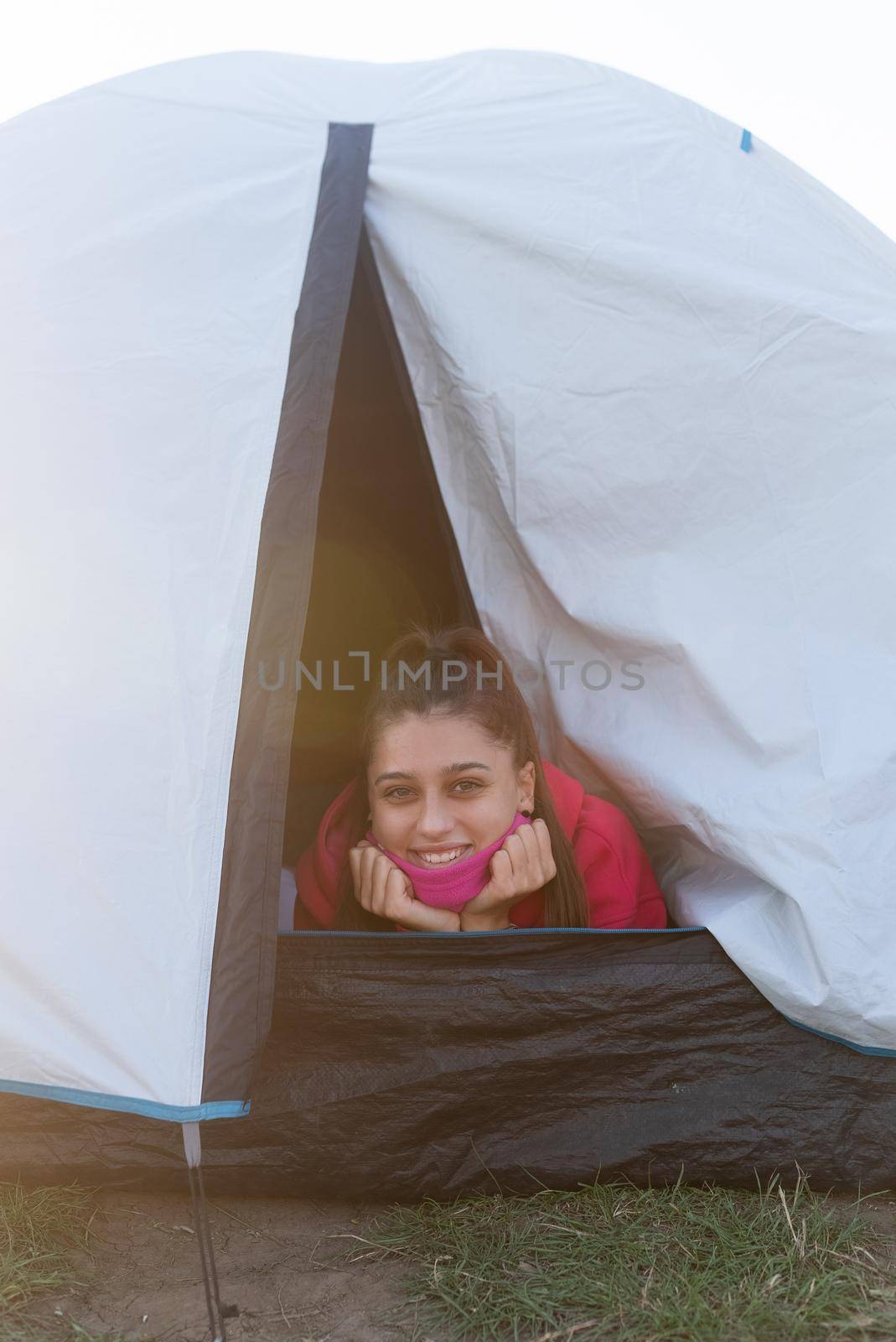 Young woman look out of tent in nature