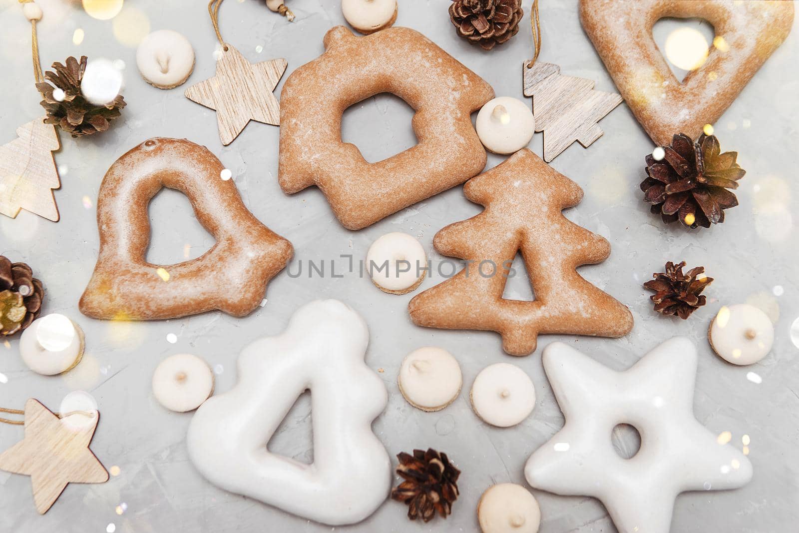 Banner for Christmas and New Year gingerbread stars, houses, Christmas trees, toys on a gray concrete background, Christmas lights bokeh in the foreground.