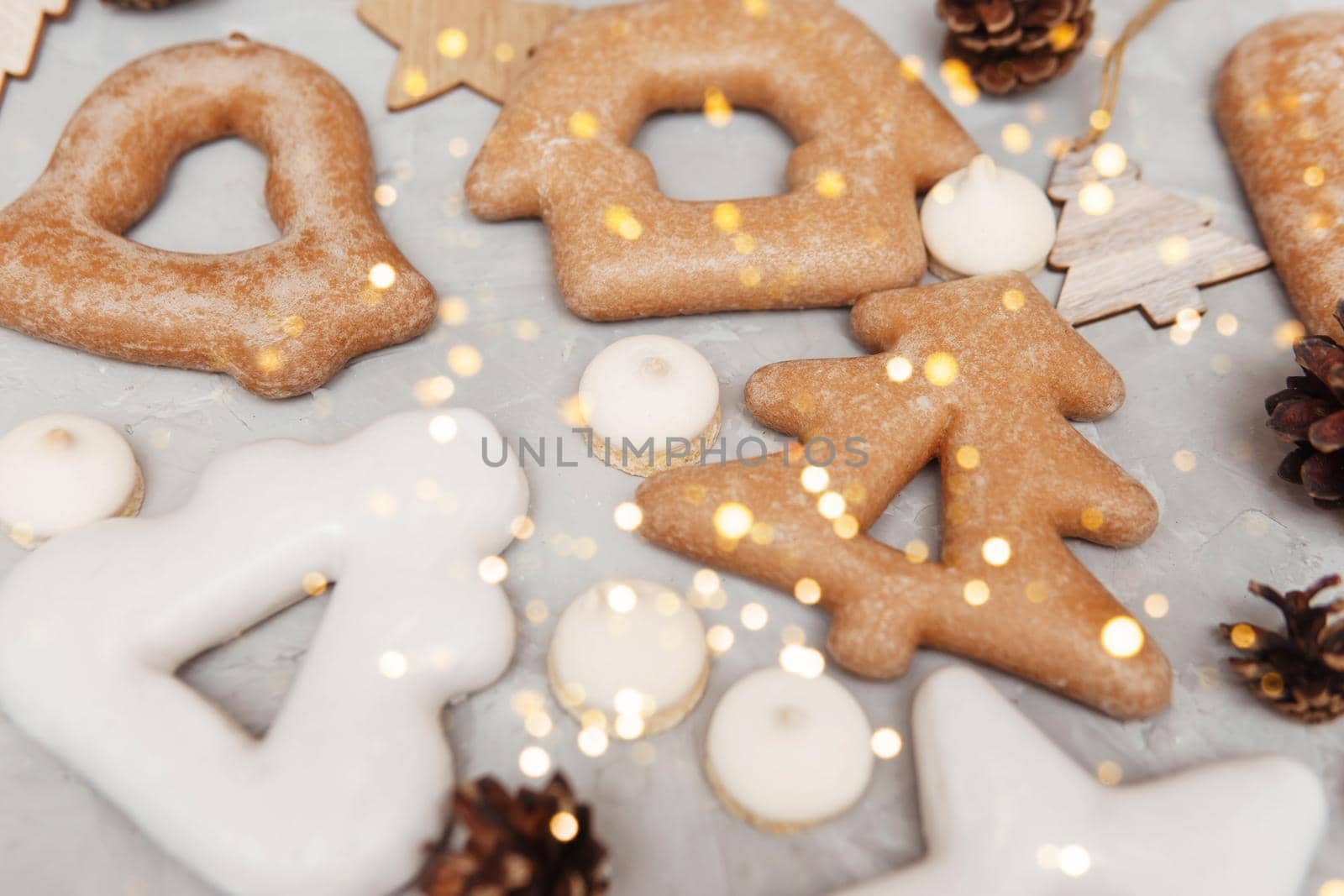 Banner for Christmas and New Year gingerbread stars, houses, Christmas trees, toys on a gray concrete background, Christmas lights bokeh in the foreground.