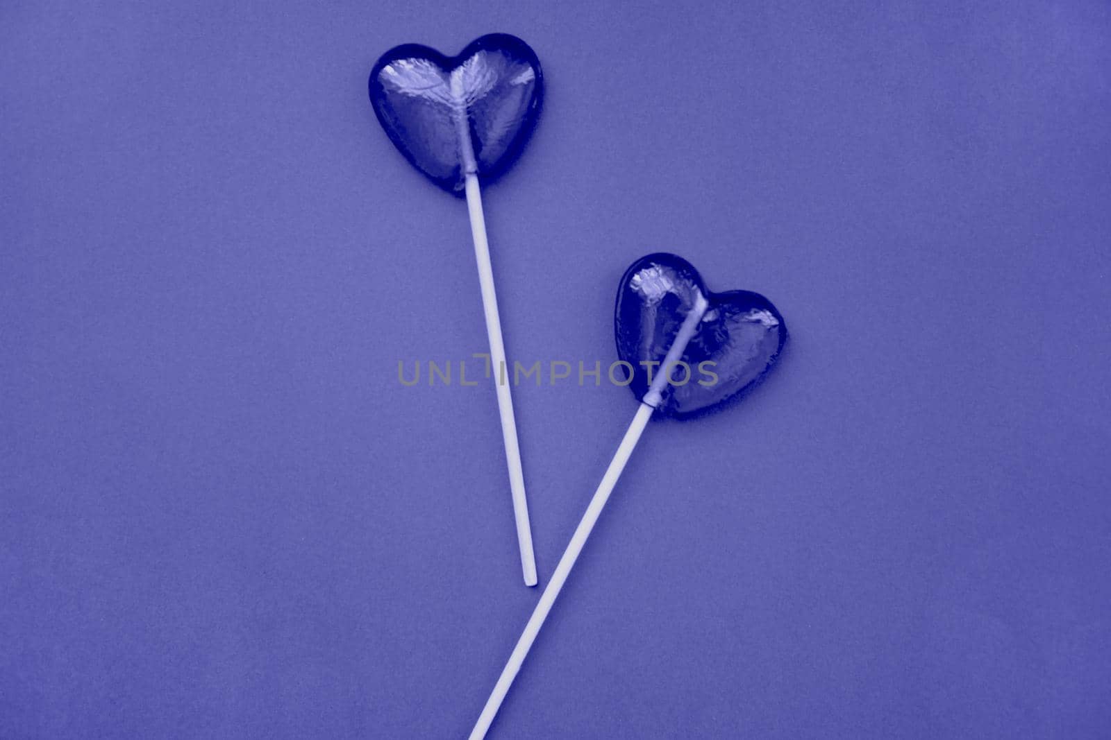 Purple lollipops in the form of hearts on a purple background. The concept of Valentine's Day. Demonstrating the colors of 2022 - Very Peri.