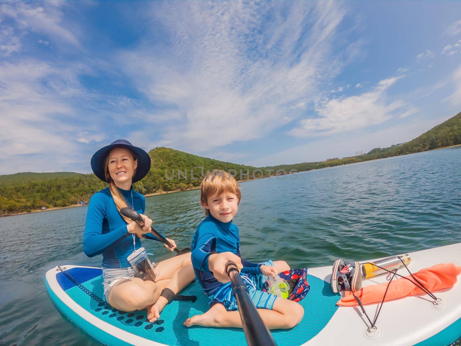 happy family of two, mother and son, enjoying stand up paddling during summer vacation.