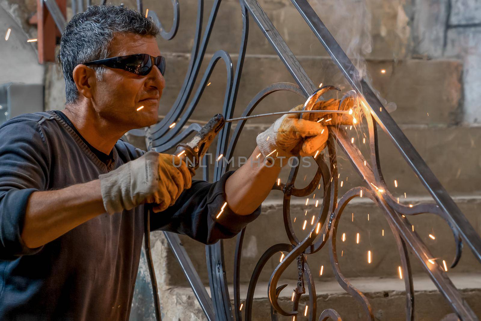 Man wearing protective glasses welds metal with welding machine in a private house. Interior welding work. Close-up.