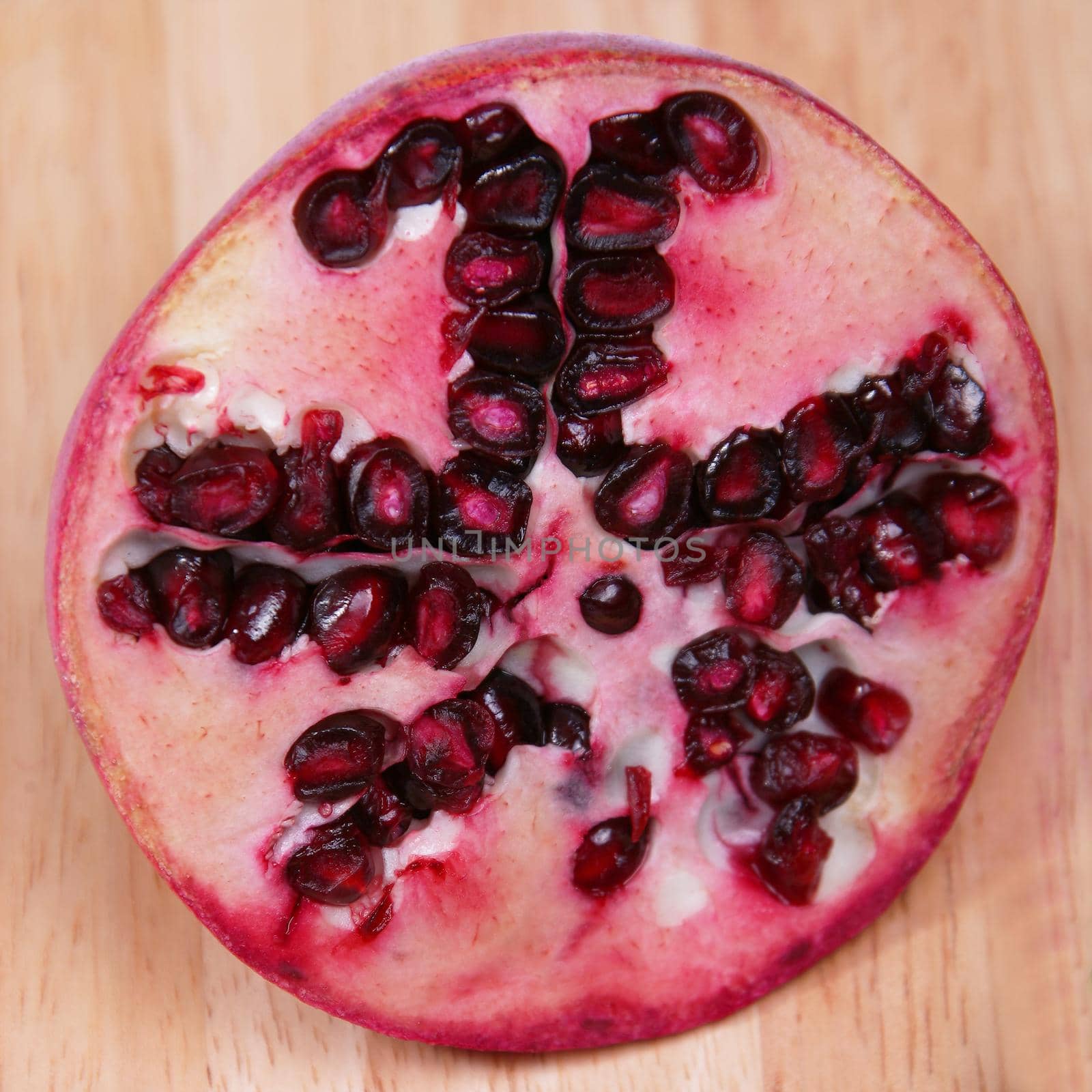 A pomegranate sliced showing seeds on a wood chopping board