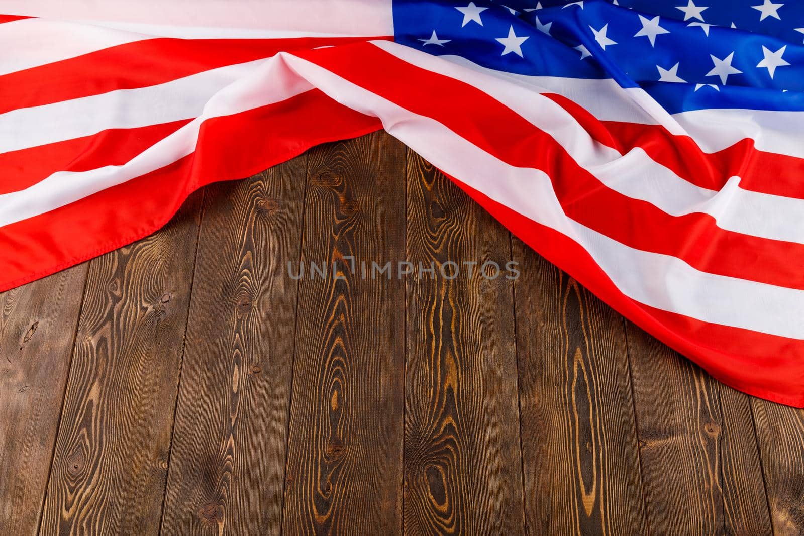 crumpled usa flag on flat textured wooden surface background.