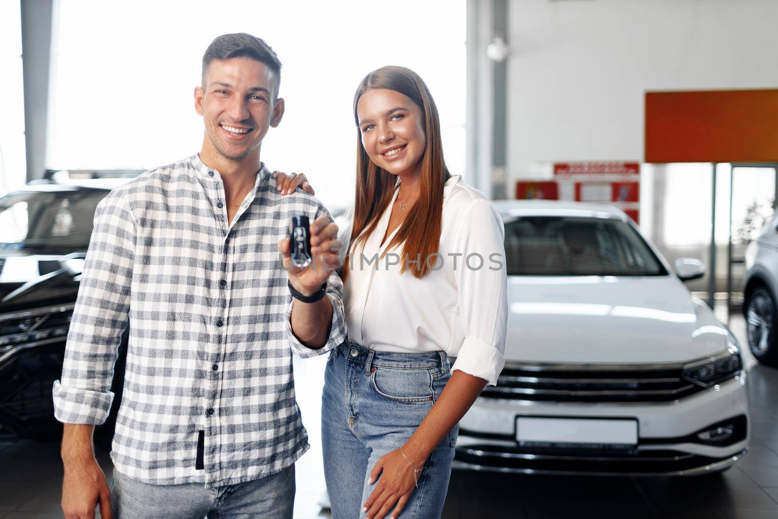 Young happy couple just bought a new car in a dealership by Fabrikasimf