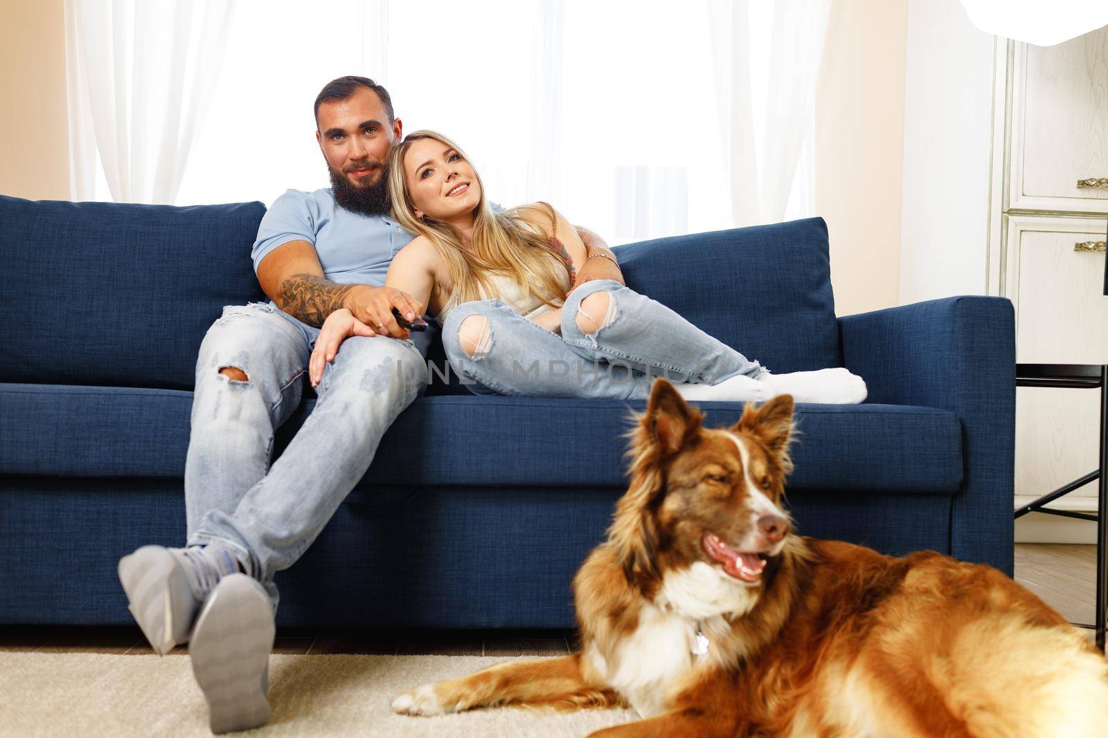 Young loving couple relaxing in living room with their Border Collie dog pet