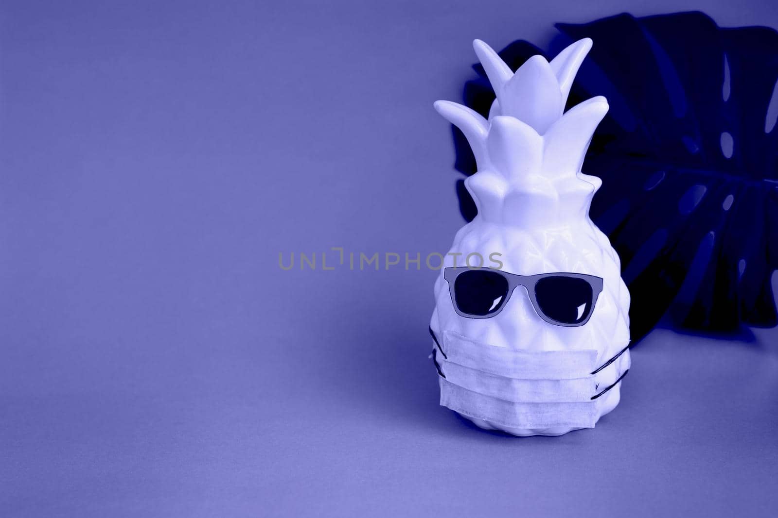 Pineapple in a medical mask and sunglasses on very peri background. Summer concept. Vision for the summer of 2022 during the coronavirus pandemic. Demonstrating the colors of 2022 - Very Peri.