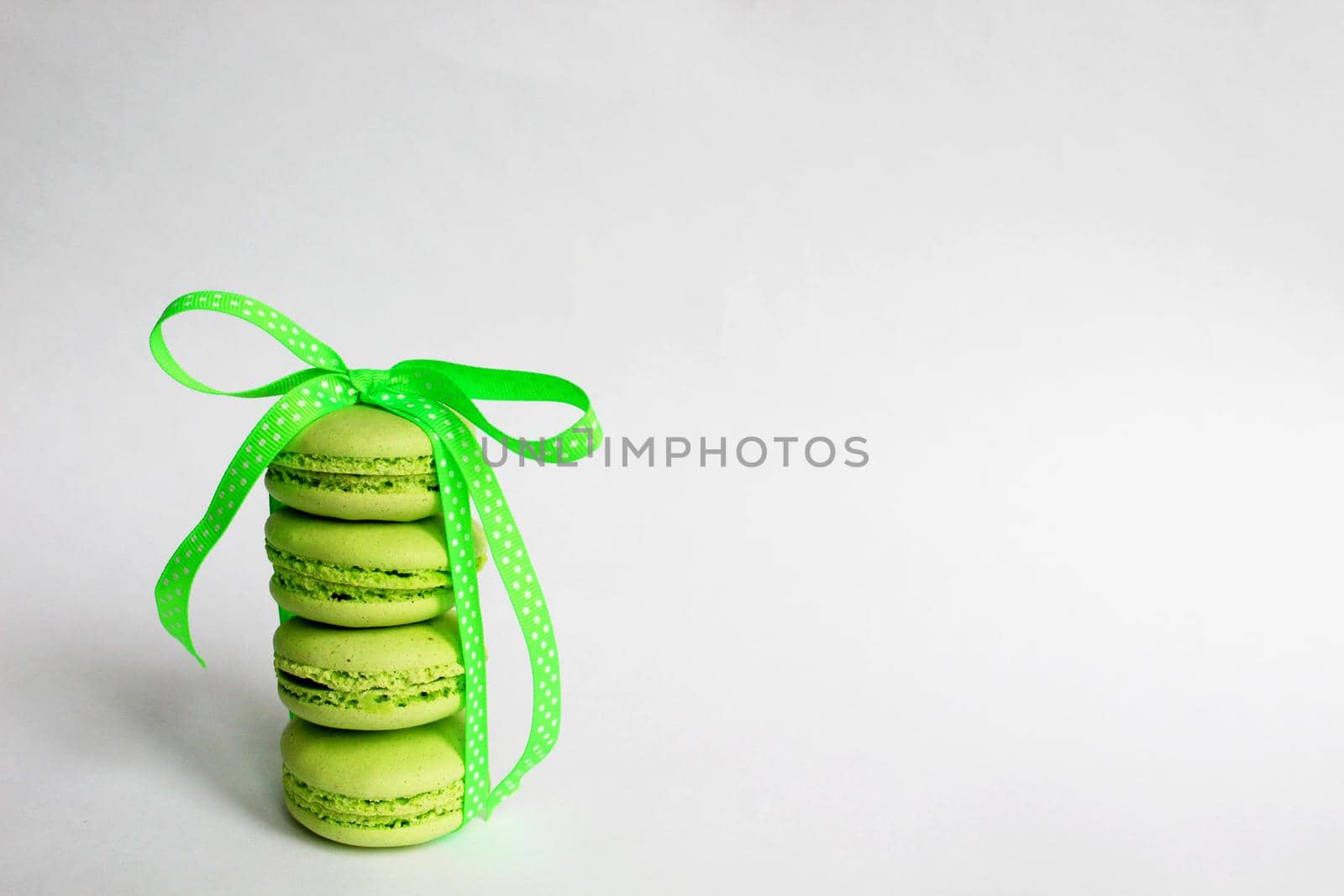 Green macaroon cakes with bright ribbon. Nice design for any purpose. White background. Place for your text. A gift for your beloved. Surprise for the holiday.