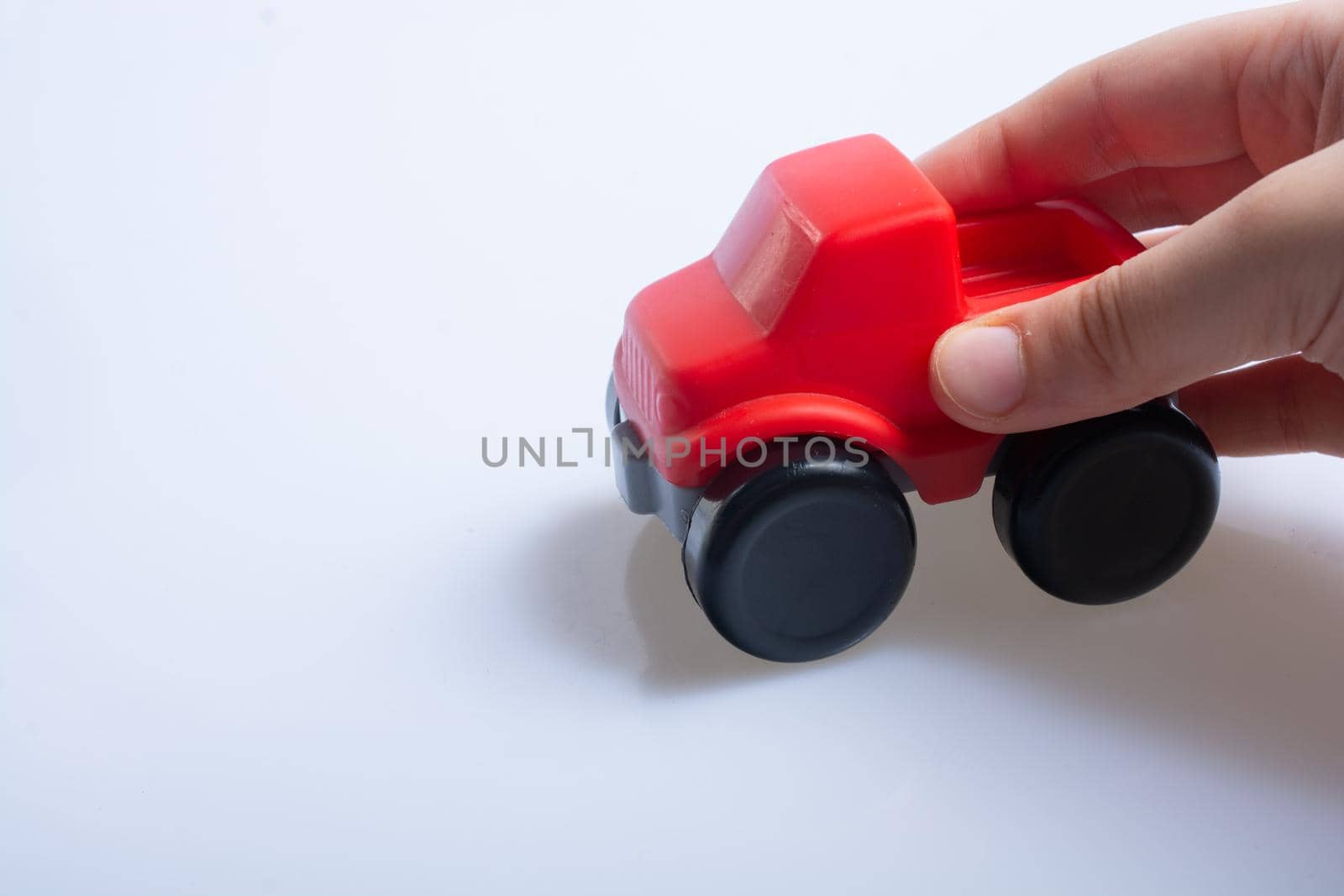 Hand plays with toy truck over white background by berkay