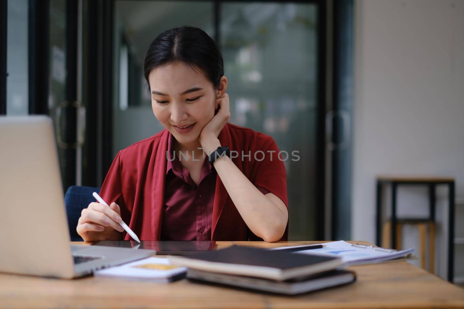 Cheerful young asian woman working with tablet. Student female in living room. online learning, studying , online shopping, freelance, asean concept.